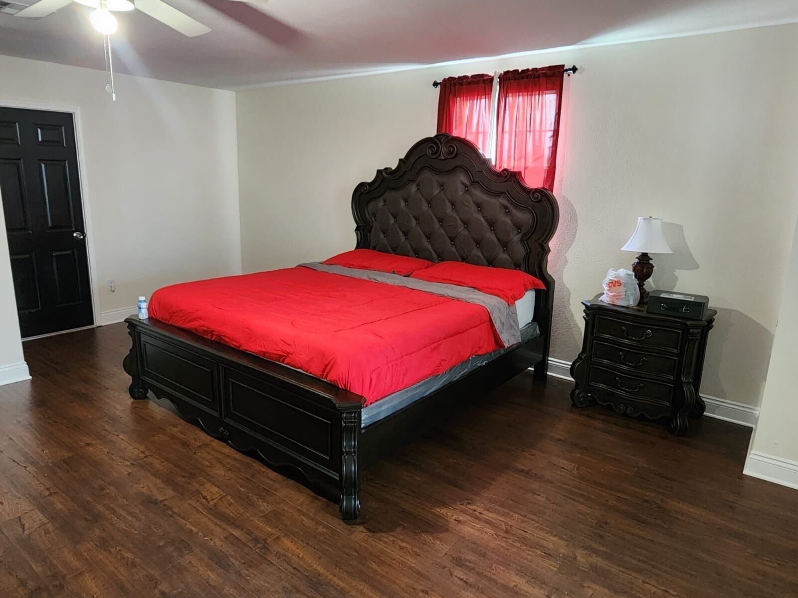A bedroom with a large bed, a nightstand, a lamp, and a door.