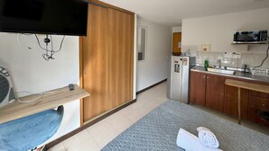 Une cuisine compacte équipée d’un four à micro-ondes, d’un réfrigérateur et d’un petit évier.