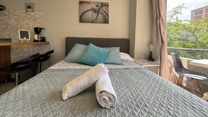 Une chambre d’hôtel avec un lit, un bureau, une chaise, une machine à café, un petit tableau noir et une affiche de vélo accrochée au mur.