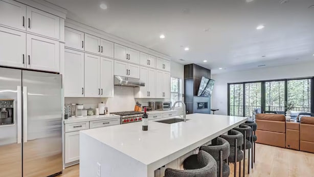 A modern kitchen with white cabinetry, a large island, and a bar area with stools. - New Modern House Built in 2024.  5 Beds and 3.5 Baths. 3020 SQFT (Flagstaff)