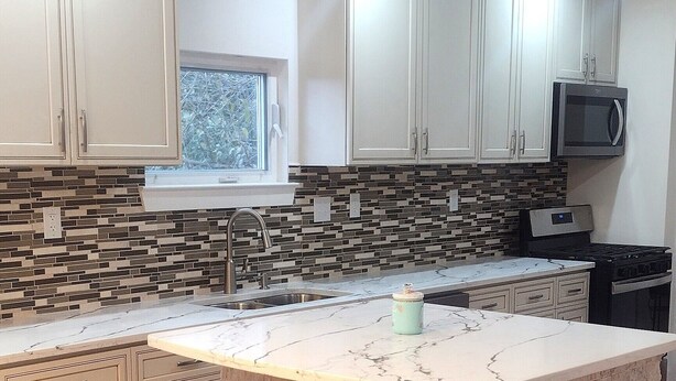 A modern kitchen with white cabinets, a marble countertop, and a built-in island. - Macon a Little Music House.  Family-sized Home <1 Mile to Mercer & Downtown (Macon)