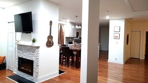 A spacious living room with a fireplace, a mounted television, and a guitar. - Macon a Little Music House.  Family-sized Home <1 Mile to Mercer & Downtown (Macon)