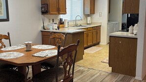 Uma cozinha com armários de madeira, uma mesa de jantar com jogos americanos e um ventilador de teto.