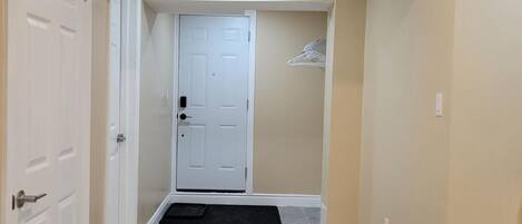 A hallway with a white door, a doormat, and a blue cleaning bucket.