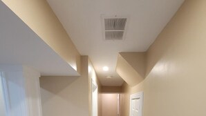 Un couloir aux murs de couleur beige, doté d’un plancher en bois et de portes blanches.