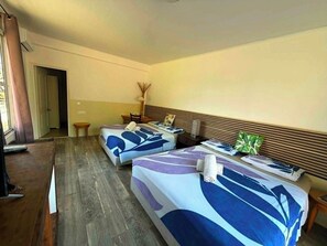 Una camera d'albergo con due letti, un tavolino, una lampada e vista all'esterno.