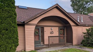 Ein Haus mit brauner Fassade, einer Veranda und einem Briefkasten.