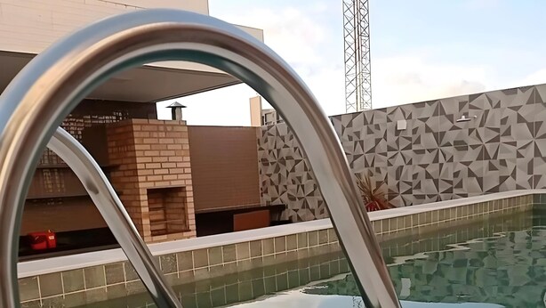 A swimming pool with a metal ladder, tiled walls, and a geometric pattern wall. - Apto a 300m da Praia de Intermares  (Cabedelo)