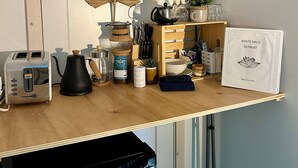 A kitchen counter with a toaster, coffee maker, kettle, and a sign for a retreat.