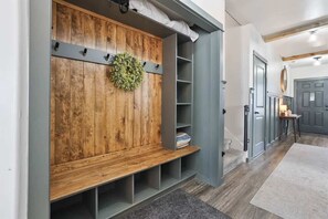 A hallway with a wooden bench, grey shelving, and a grey door.