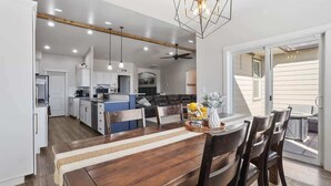 A spacious kitchen with modern appliances, a dining area with a wooden table and chairs, and a large sliding glass door leading to an outdoor area.
