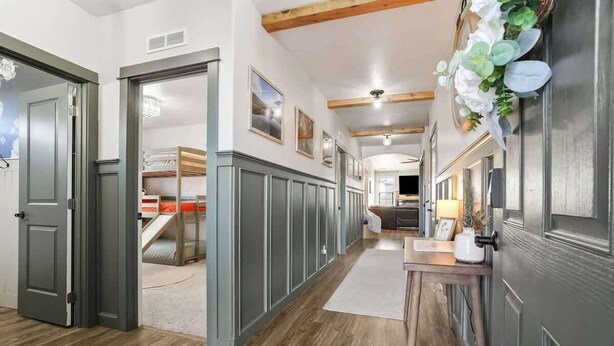 A hallway with a wooden floor, grey walls, and a staircase leading to a bedroom.