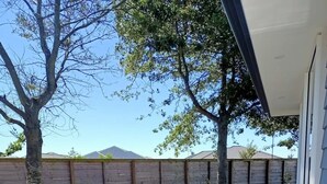 An outdoor patio with a concrete floor, two black metal chairs, and a glass table.
