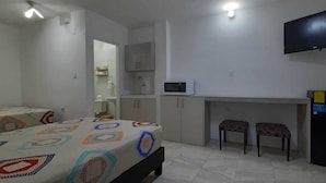 Un dormitorio con dos camas, un escritorio con silla, televisor y refrigerador.