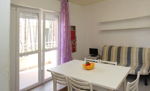 A room with a white table, white chairs, a striped sofa, and a purple curtain. - A Calm Escape Close to the Beach - Beahost (San Michele al Tagliamento)
