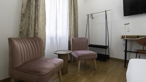 Een hotelkamer met een bed, twee stoelen, een klein rond tafeltje, een televisie en een schommel.
