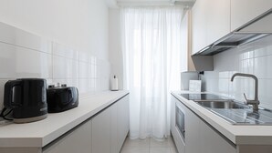 Een moderne keuken met witte kasten, een roestvrijstalen spoelbak en een koffiezetapparaat.