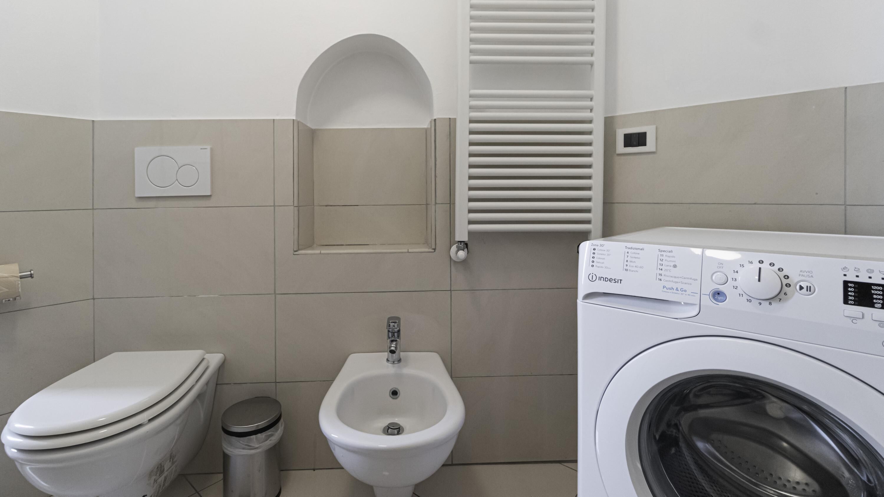 Un baño con inodoro, bidé y lavadora.