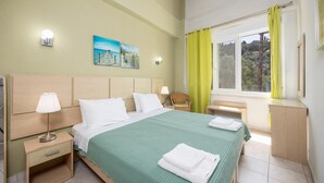 Siististi järjestetty hotellihuone, jossa on sänky, yöpöydät, tuoli, työpöytä ja ikkuna, jossa on verhot.