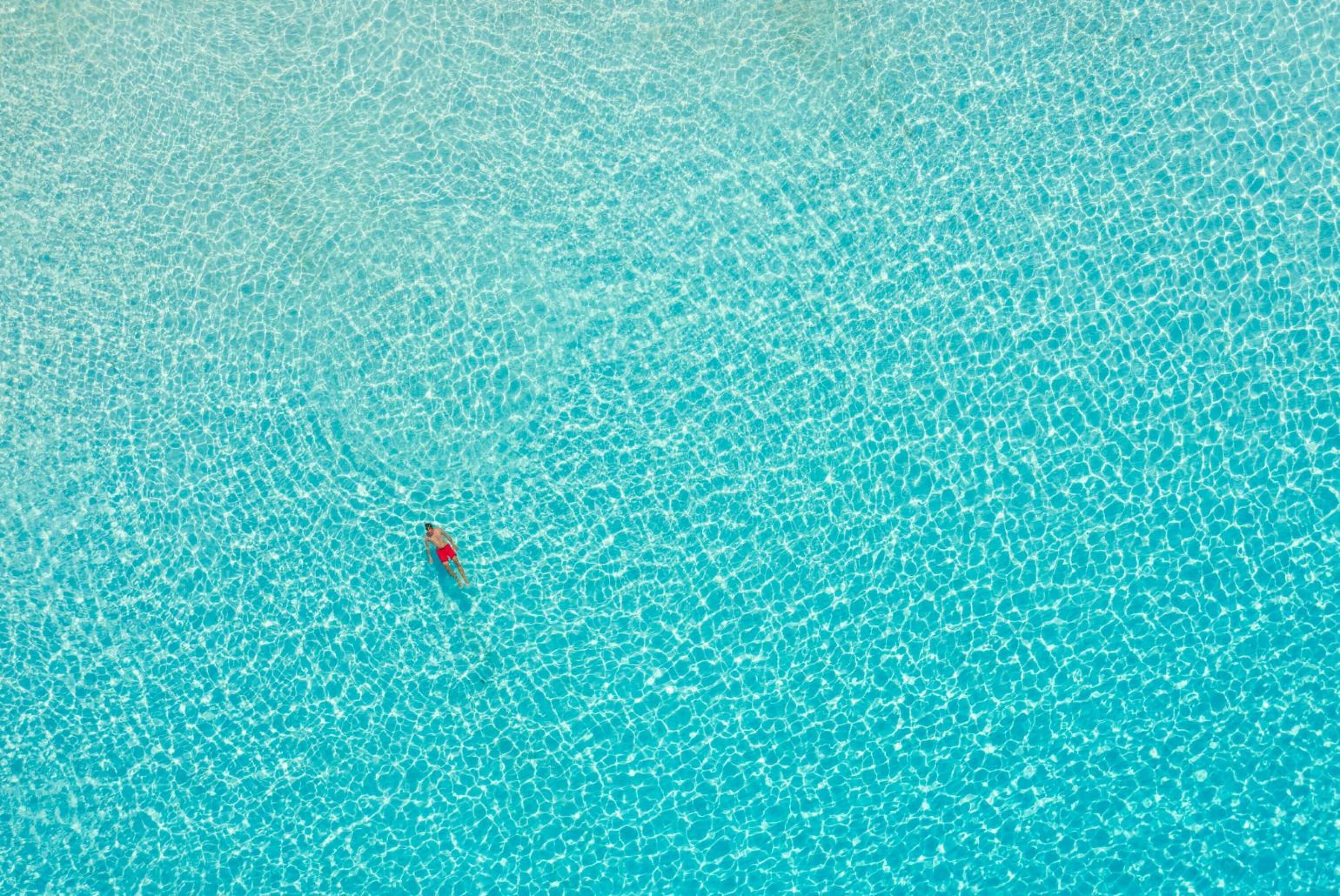 Une piscine d’eau bleue et limpide dans laquelle se trouve une personne.