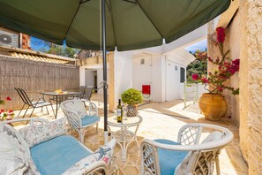 A patio with outdoor furniture, a table with a bottle, and a potted plant. - Niki Studio Tria in Lakka (Paxos)