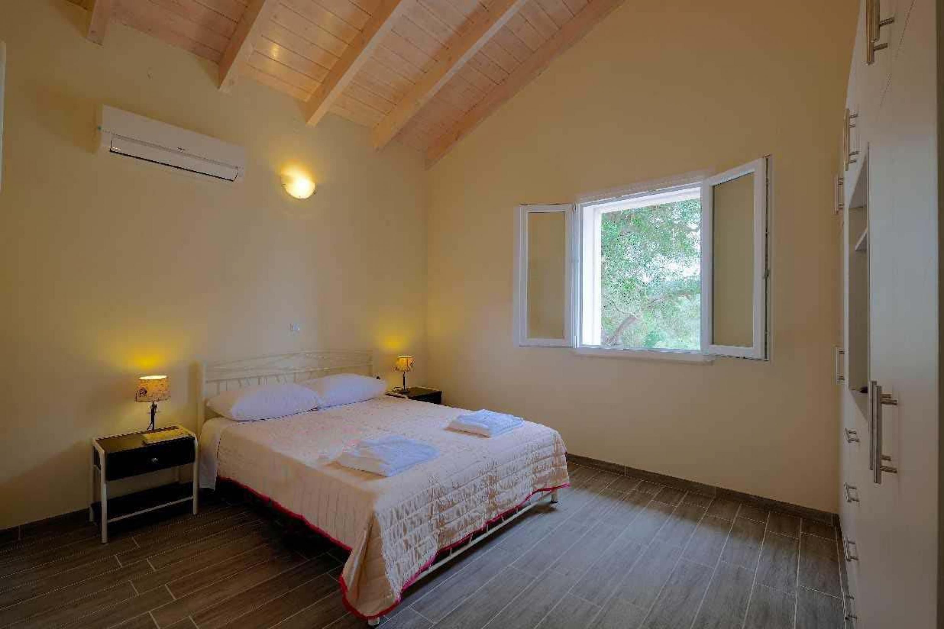 Een slaapkamer met een bed, nachtlampjes, een raam en een airconditioning.