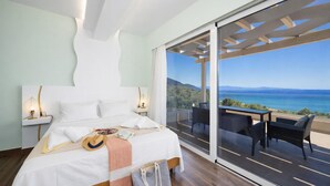 A bedroom with a large bed, a nightstand, a bedside table, a window with a view of the sea, and a balcony with outdoor furniture. - Villa Alora in Mparmpati (Corfu)
