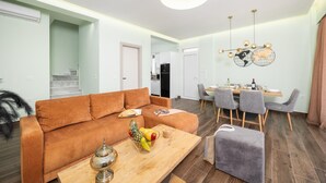 A modern living room with a sofa, coffee table, and dining area with chairs and a table. - Villa Alora in Mparmpati (Corfu)