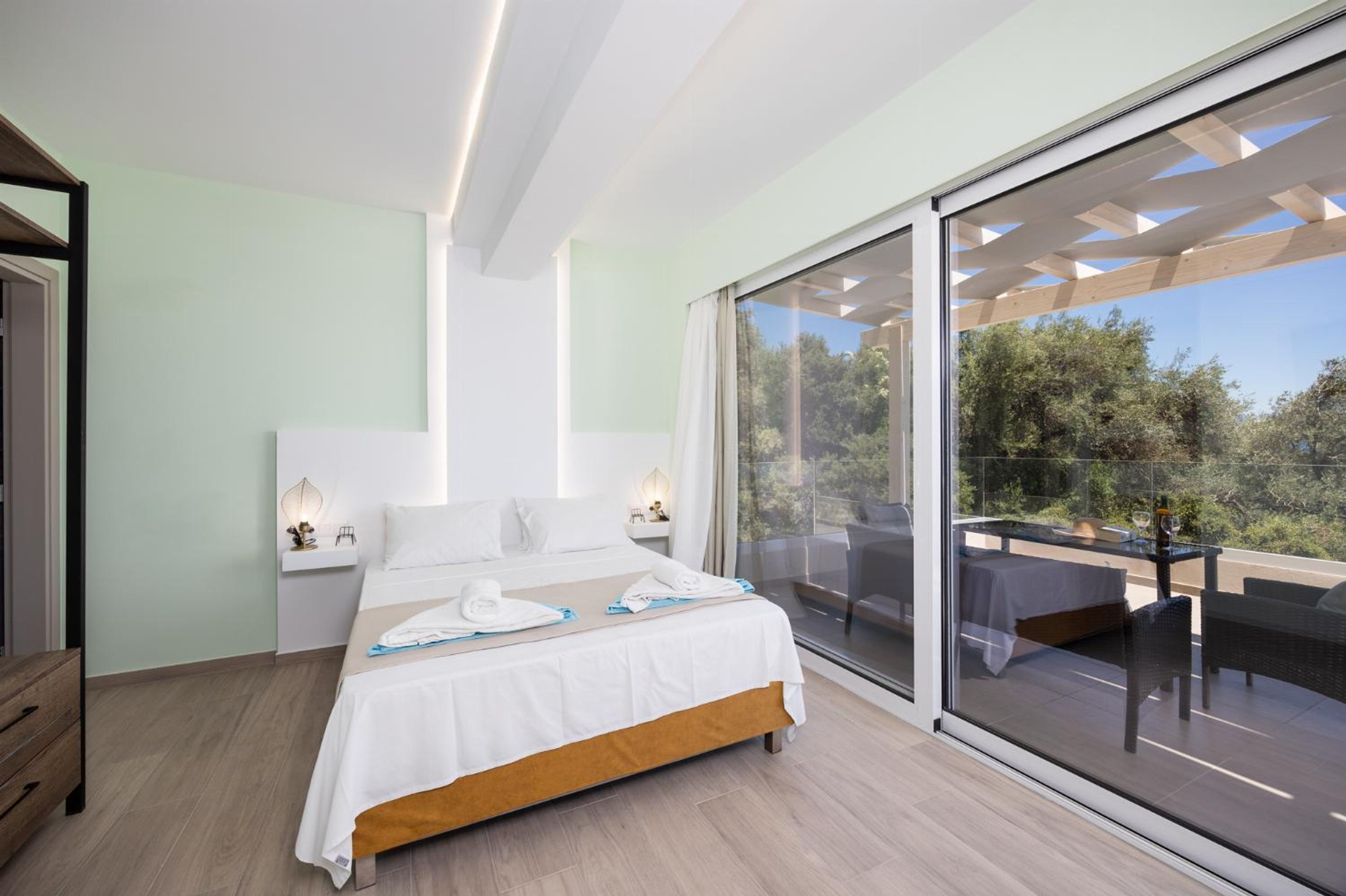 Un dormitorio moderno con una cama grande, lámparas de noche y vistas a un balcón exterior.