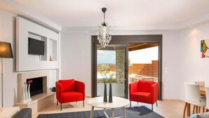 Ein modernes Wohnzimmer mit Kamin, zwei roten Sesseln, einem runden Couchtisch und einem großen, an der Wand befestigten Fernseher.