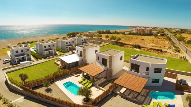 Ein moderner Wohnkomplex mit mehreren Häusern, einem Schwimmbad und Blick aufs Meer.