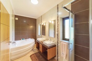 Een moderne badkamer met een vrijstaand bad, twee wastafels en een grote spiegel.