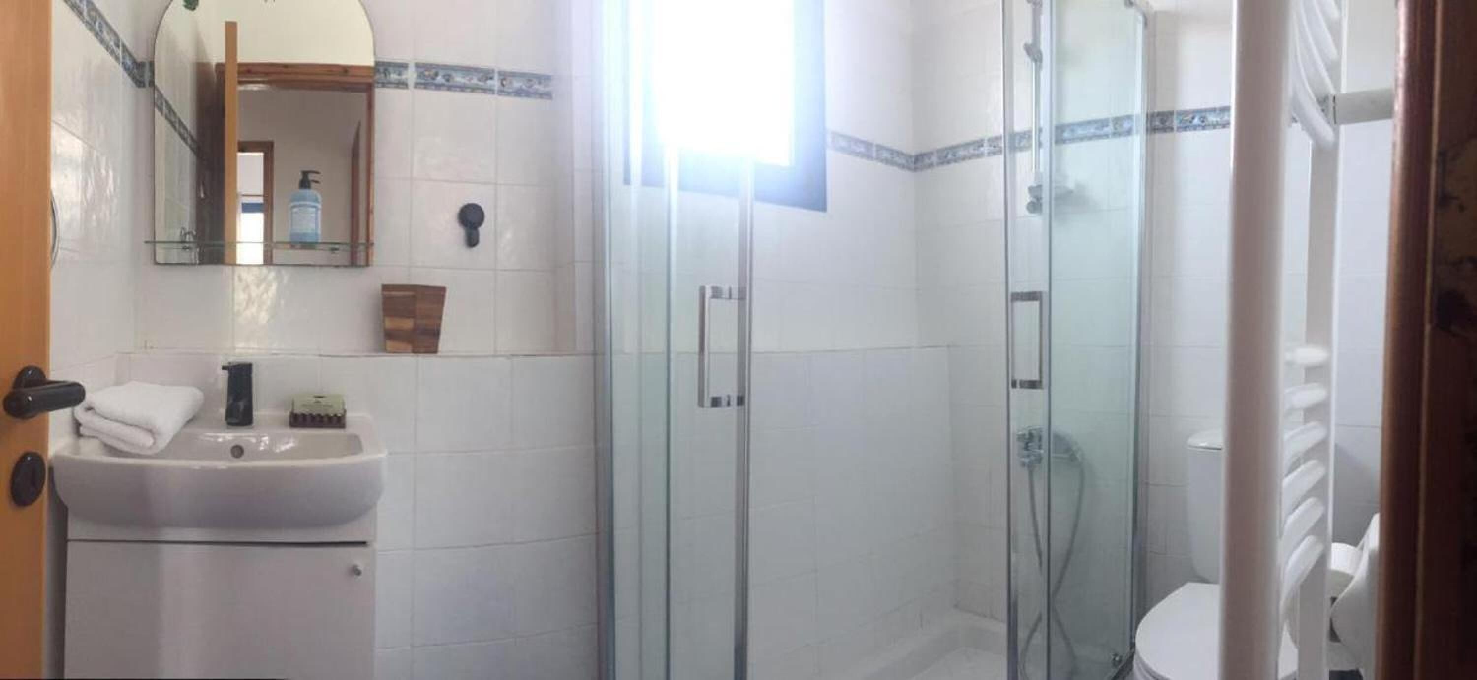 A bathroom with a glass-enclosed shower, a sink with a mirror, and a toilet.