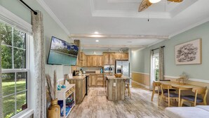A spacious kitchen with wooden cabinets, a central island, and a dining area with a table and chairs.