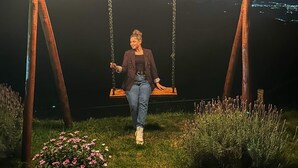 A person sitting on a swing under a wooden structure with lights, surrounded by greenery and flowers. - Chalé Sol no Horizonte  (Corrego do Bom Jesus)