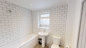 A bathroom with white subway tiles, a bathtub, a sink, and a toilet. - Central, Stunning 3-Bed House - Free Parking (Sunderland)