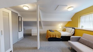A compact, well-lit room with a bed, a sofa, a small desk, and a wardrobe. - Central, Stunning 3-Bed House - Free Parking (Sunderland)