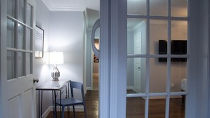 Une pièce comprenant une table à manger, des chaises, une lampe et un téléviseur fixé au mur.