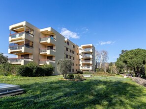 A multi-story residential building with balconies, surrounded by a well-maintained garden with grass and small trees. - Parcs du Lavandou by Interhome (Le Lavandou)