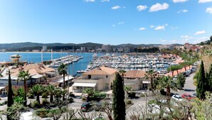 A marina with numerous boats docked, surrounded by buildings and palm trees.