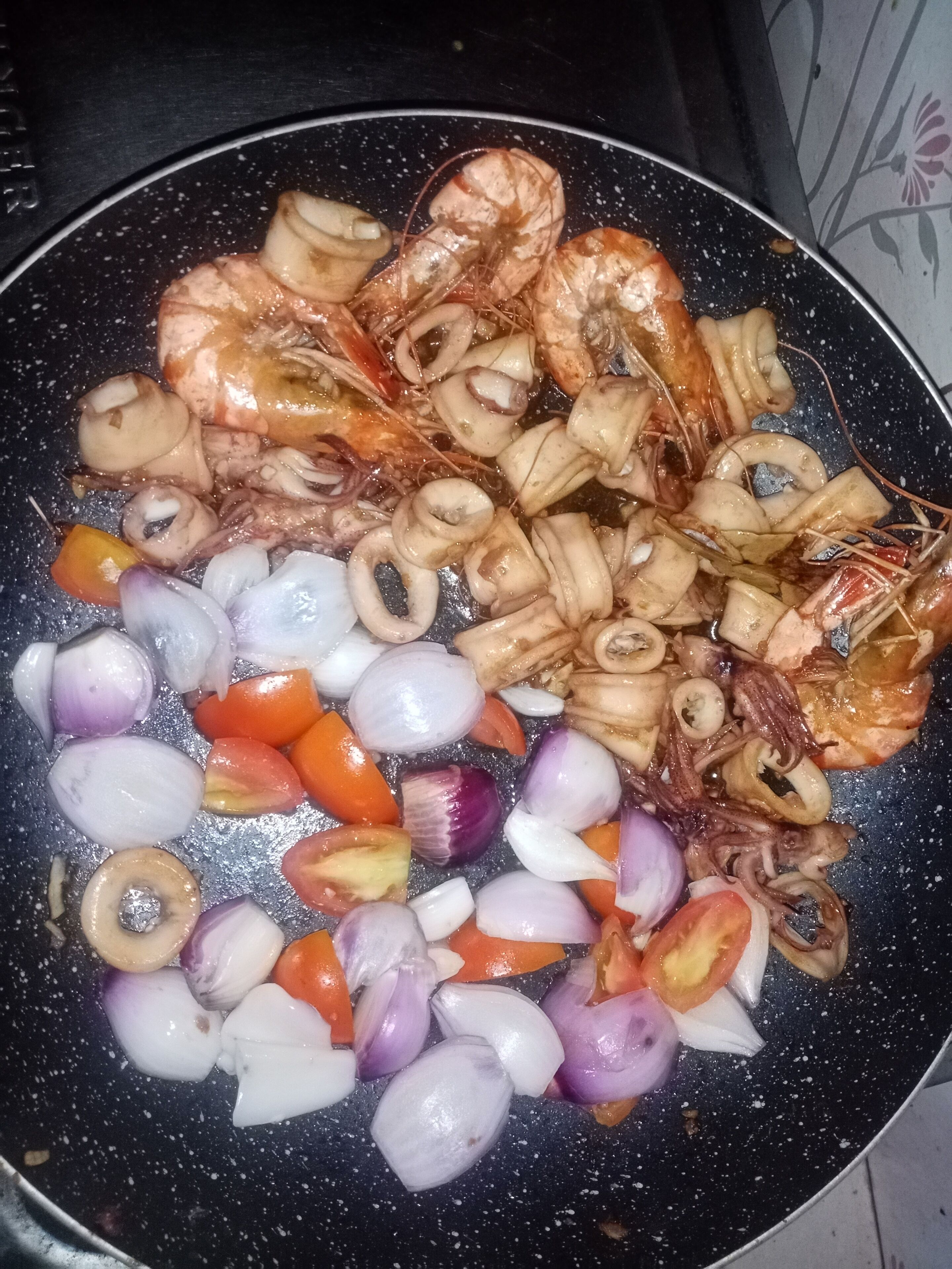 A pan with shrimp, squid, and sliced vegetables.