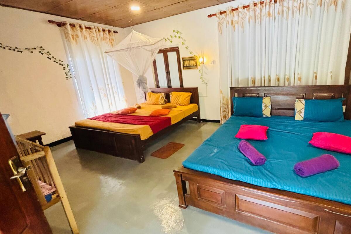A bedroom with two beds, a wooden headboard, and a mosquito net.