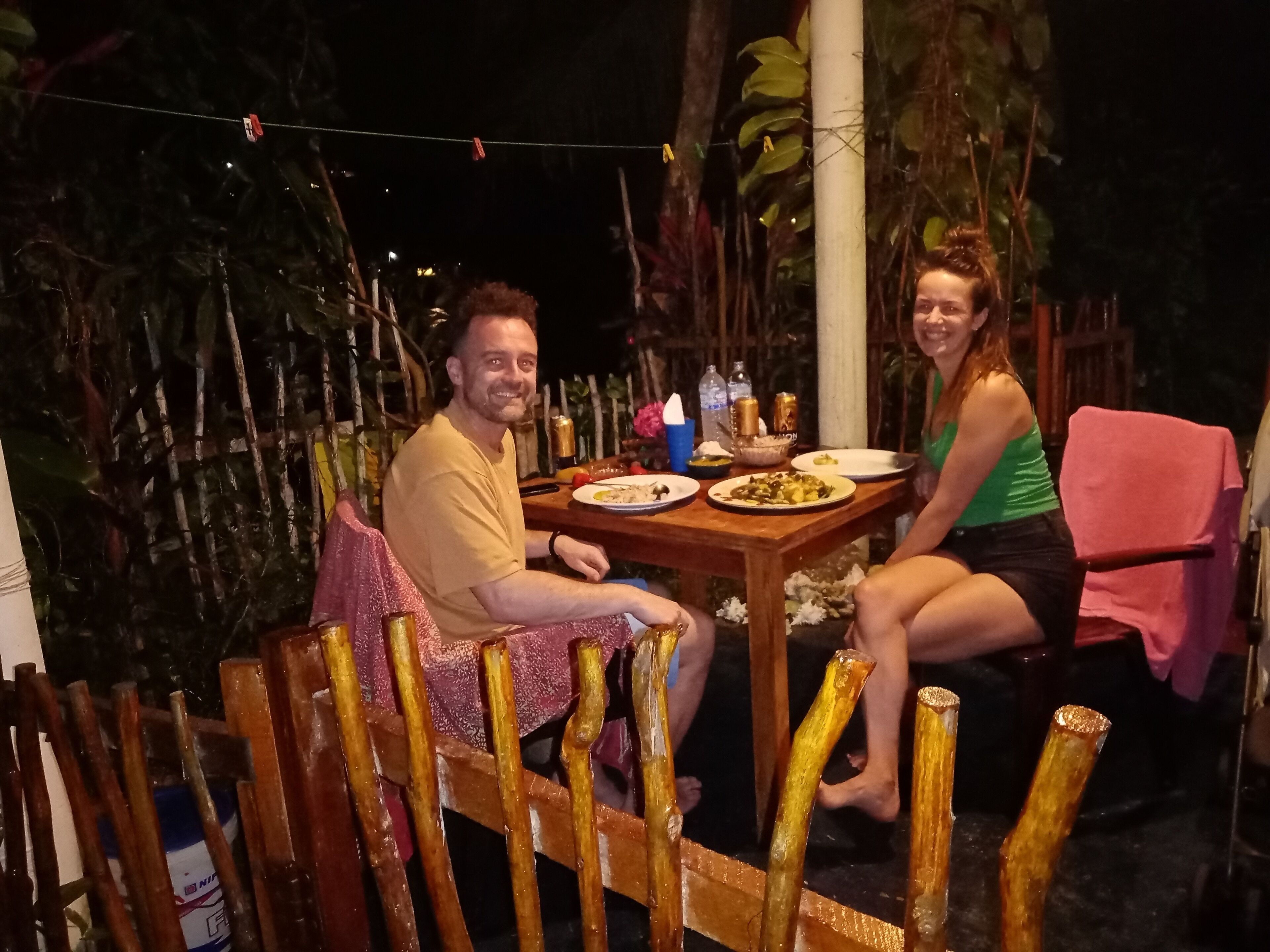Mesa de jantar de madeira ao ar livre com duas pessoas sentadas.