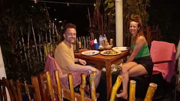 Mesa de jantar de madeira ao ar livre com duas pessoas sentadas.