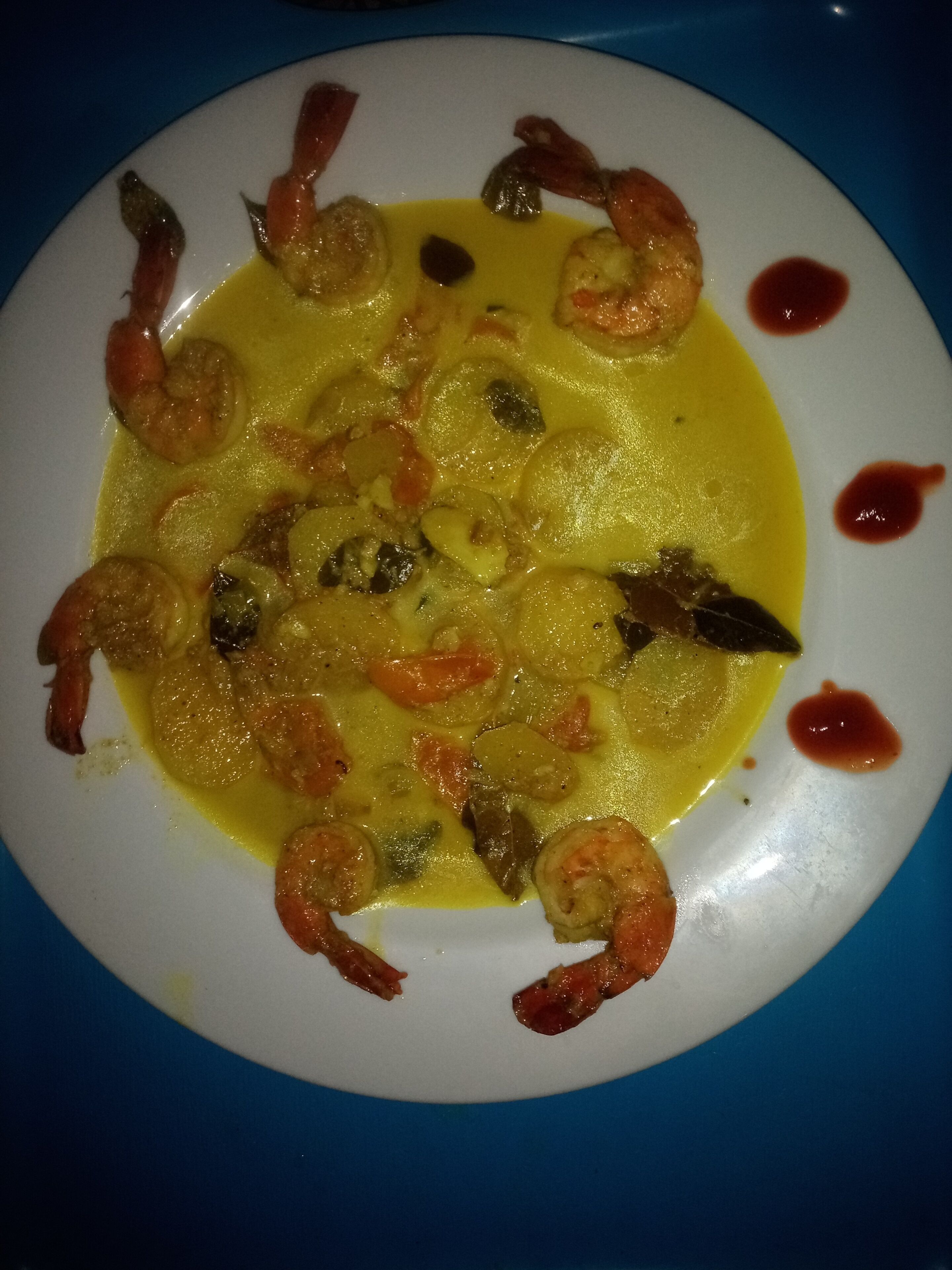 A plate of shrimp and vegetables in a yellow sauce.