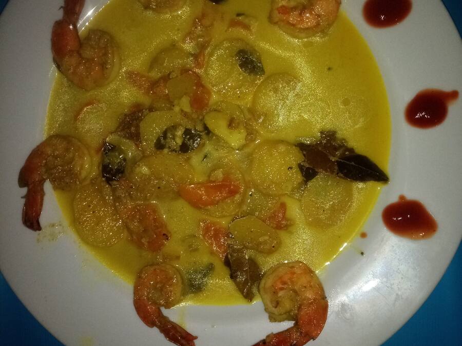 A plate of shrimp and vegetables in a yellow sauce.