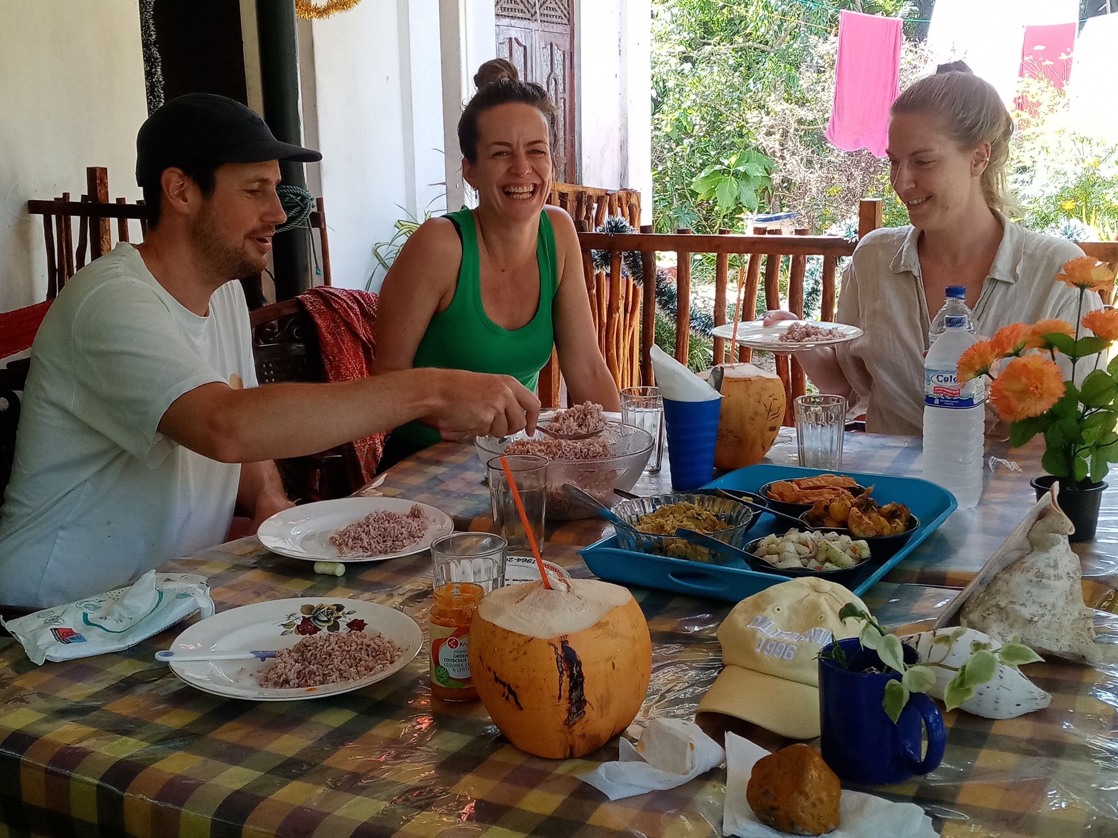Una mesa de comedor con platos de comida, una bebida de coco y una botella de agua.