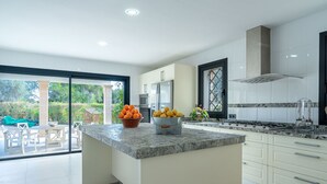 A modern kitchen with white cabinets, a granite countertop, and a large island with fruit bowls. - Ca na Saurina by Interhome (Crestatx)
