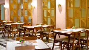 A restaurant with multiple tables and chairs, wooden partitions with geometric patterns, and wall-mounted light fixtures. - Portola Arabia Hotel Banda Aceh  (Banda Aceh)