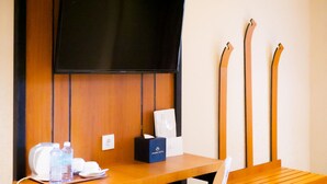 A hotel room with a wooden desk, a television mounted on the wall, and skis leaning against the wall. - Portola Arabia Hotel Banda Aceh  (Banda Aceh)